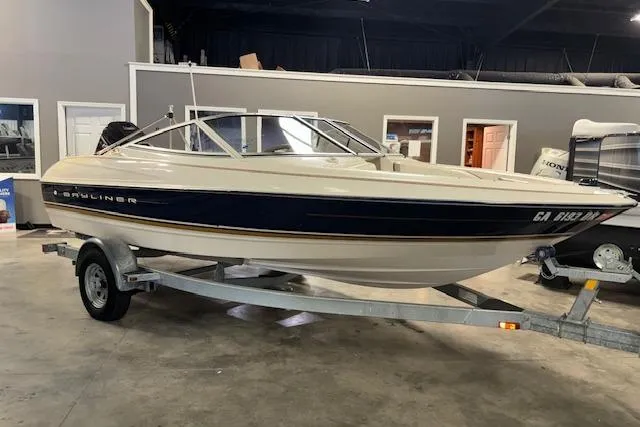The Image of 1996 Bayliner 1700 LS boat on trailer in indoor showroom setting. - 0