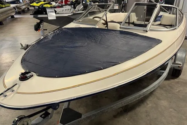 Slide: The Image of 1996 Bayliner 1700 LS boat with cover, displayed indoors on a trailer. - 7