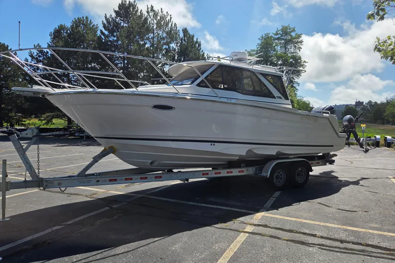 Slide: The Image of 2026 Cutwater C-248 Coupe boat on trailer in parking lot, surrounded by trees. - 7