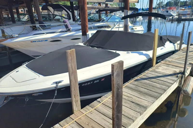 Slide: The Image of 2005 Sea Ray 270 SLX boat docked, covered with black canvas, in a marina setting. - 0