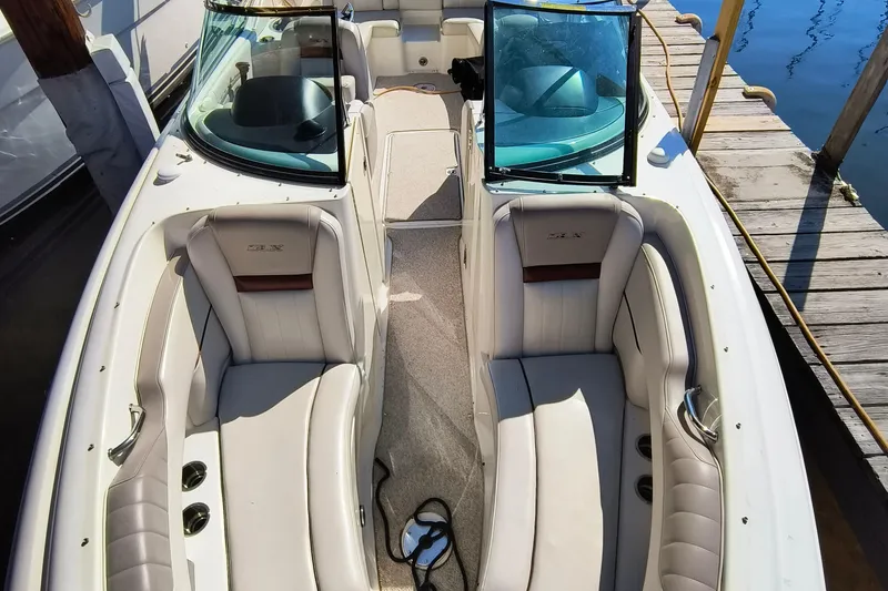 Slide: The Image of 2005 Sea Ray 270 SLX boat interior with white seating and open windshield at dock. - 4