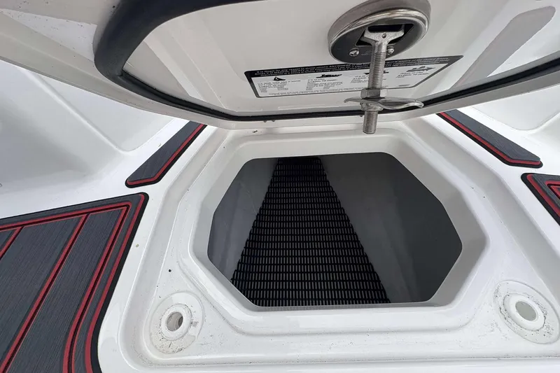 Slide: The Image of Open storage compartment on 2026 Monterey Elite 30 OB boat with red and gray trim. - 17