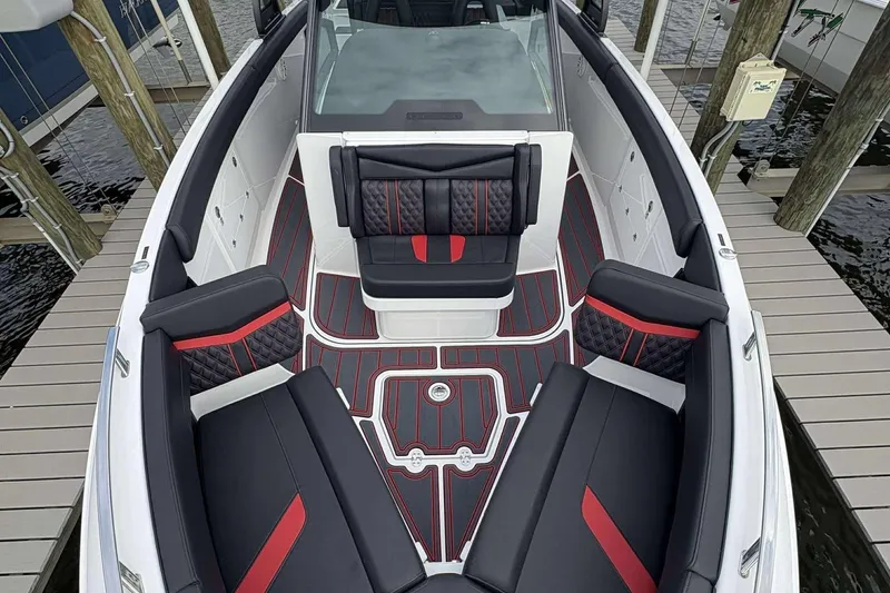 Slide: The Image of 2026 Monterey Elite 30 OB boat interior with black and red seating, docked by wooden piers. - 5