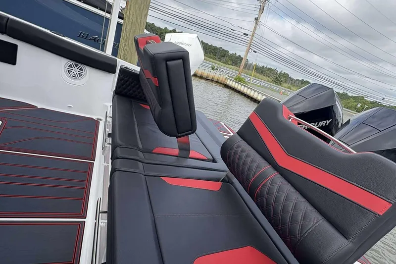 Slide: The Image of Luxury seating on 2026 Monterey Elite 30 OB boat, featuring black and red upholstery. - 6