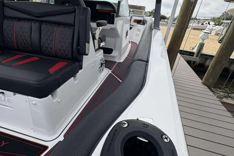 Slide: The Image of 2026 Monterey Elite 30 OB boat interior with black and red seating, docked at a marina. - 9