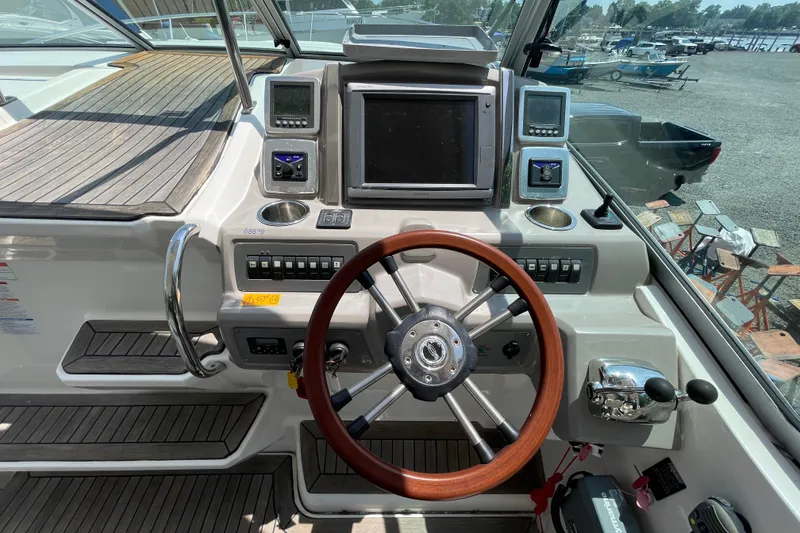 Slide: The Image of 2011 Chaparral 330 Signature boat helm with wooden steering wheel and navigation controls. - 12