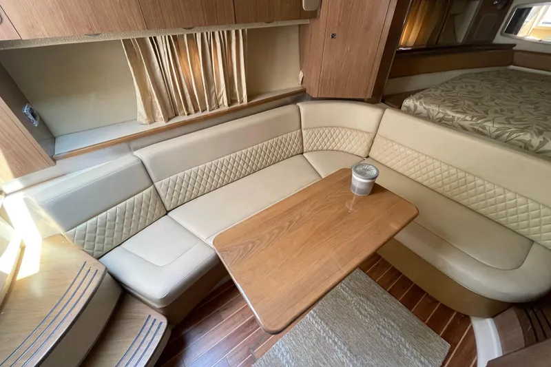 Slide: The Image of 2011 Chaparral 330 Signature interior with beige seating, wooden table, and cozy cabin layout. - 23