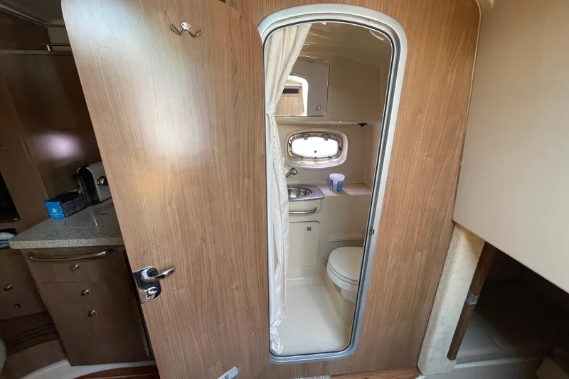Slide: The Image of 2011 Chaparral 330 Signature boat bathroom with wooden door, sink, and toilet. - 29