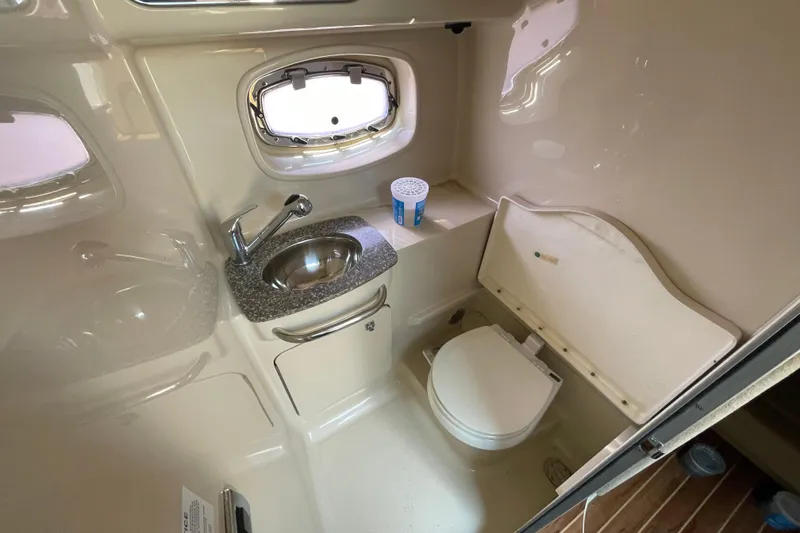 Slide: The Image of 2011 Chaparral 330 Signature boat bathroom with sink, toilet, and porthole window. - 30