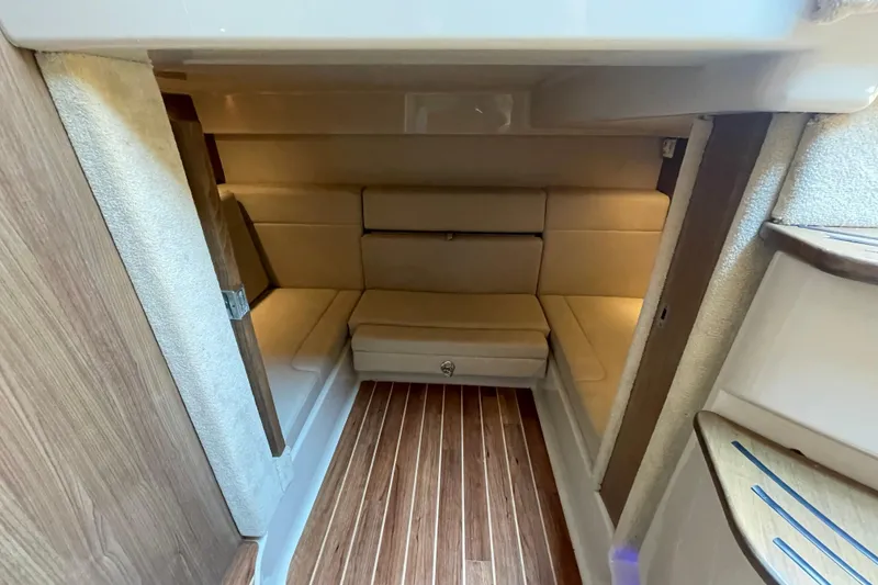 Slide: The Image of 2011 Chaparral 330 Signature cabin interior with beige seating and wooden flooring. - 31