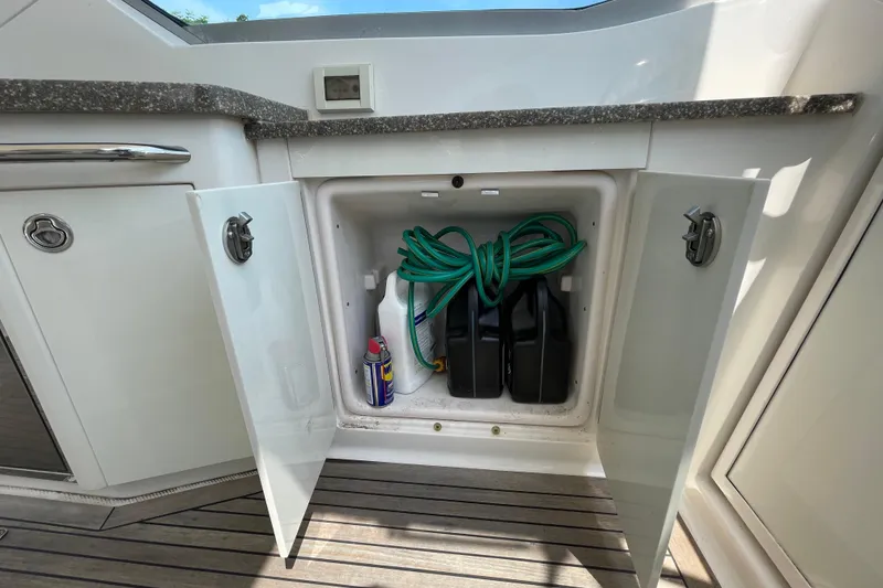 Slide: The Image of Storage compartment on a 2011 Chaparral 330 Signature boat with cleaning supplies and hose. - 37