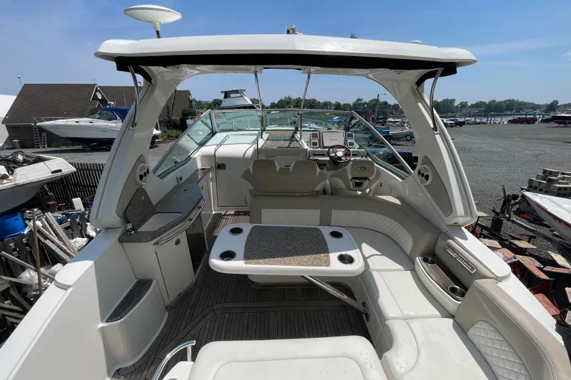 Slide: The Image of 2011 Chaparral 330 Signature boat interior with seating, table, and helm in marina setting. - 4
