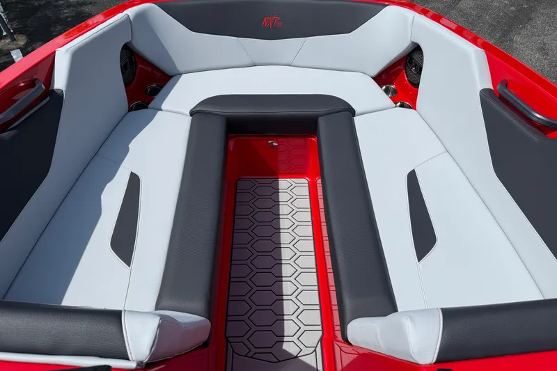 Slide: The Image of 2025 MasterCraft NXT24 boat interior with red and gray seating and hexagonal floor design. - 11