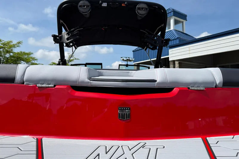 Slide: The Image of 2025 MasterCraft NXT24 boat, red exterior, rear view with seating and tower speakers. - 9