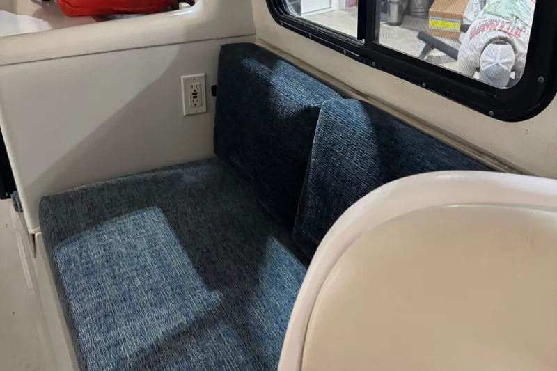 Slide: The Image of 2001 Adventure Craft 2800 Cabin Yacht interior with blue cushioned seating and window view. - 11