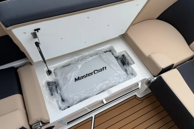 Slide: The Image of 2025 MasterCraft X24 boat storage compartment with cushioned seating and sleek design. - 16