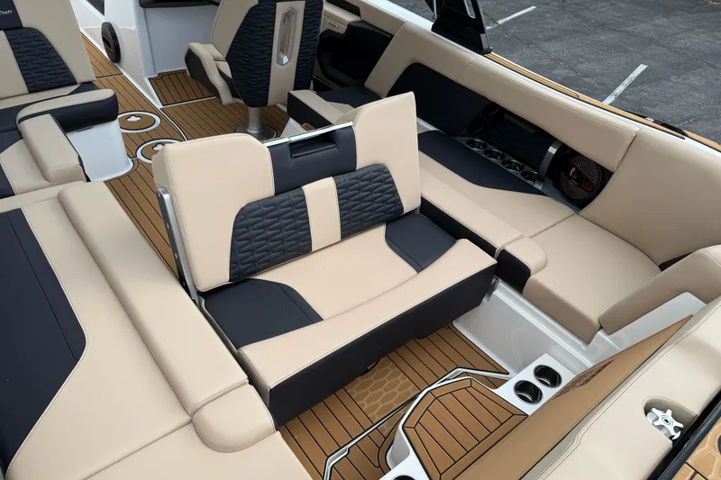 Slide: The Image of 2025 MasterCraft X24 boat interior with beige and black seating, wood-style flooring. - 18