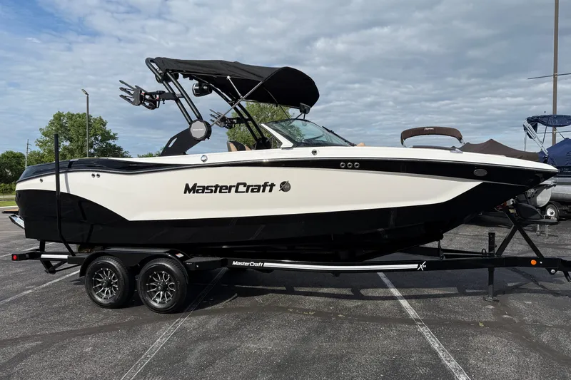 Slide: The Image of 2025 MasterCraft X24 boat on trailer, parked outdoors under cloudy sky. - 3