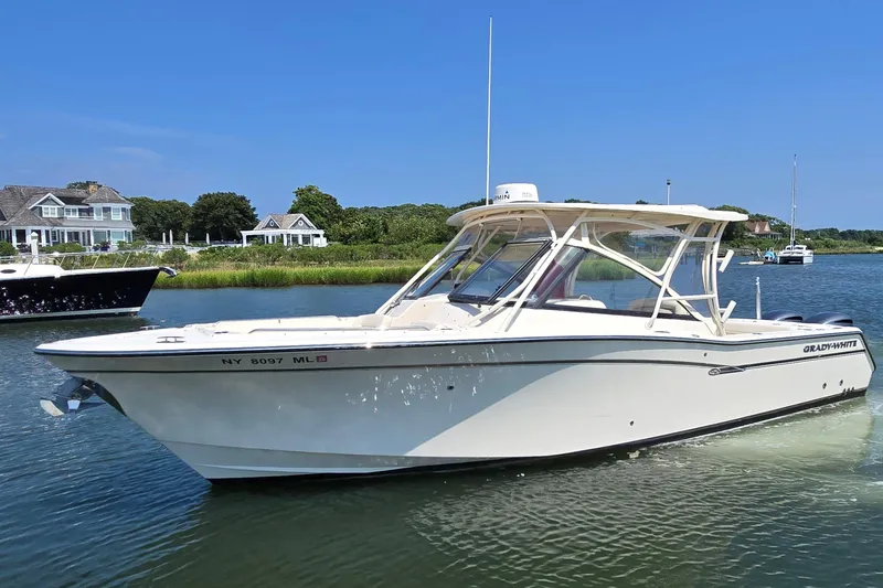 Slide: The Image of 2016 Grady-White Freedom 307 boat on calm water near shoreline homes. - 1