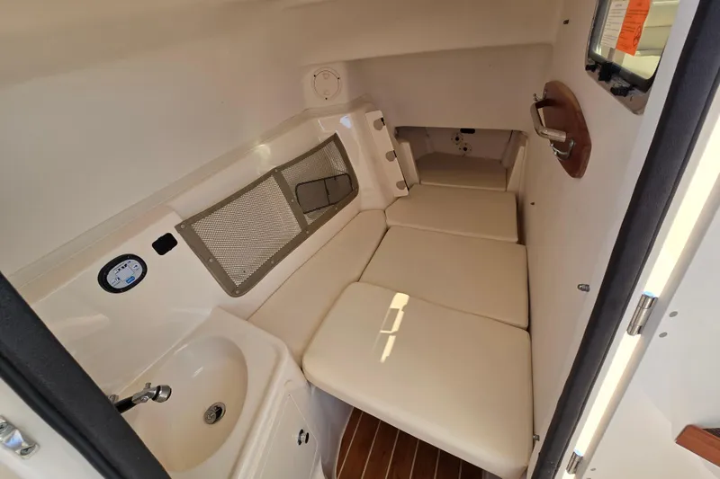 Slide: The Image of 2016 Grady-White Freedom 307 cabin interior with cushioned seating and compact sink. - 16