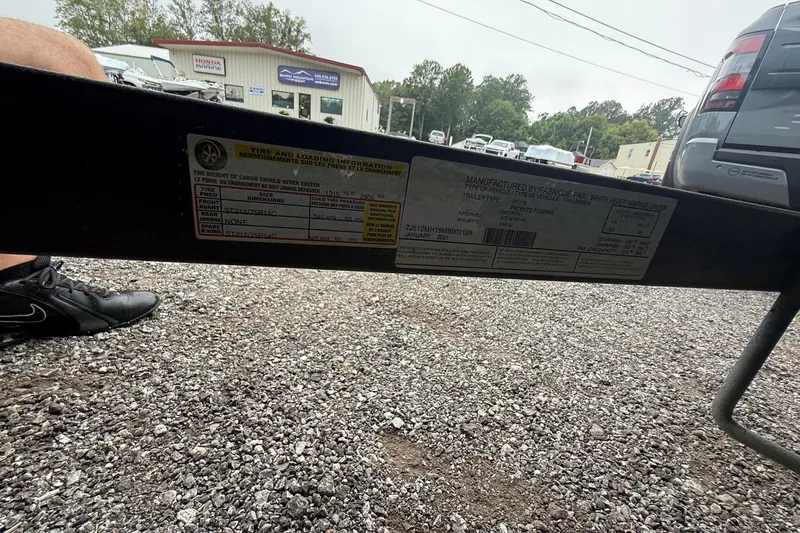 Slide: The Image of 2021 Ranger RT178 trailer label with tire and loading information, parked on gravel. - 19