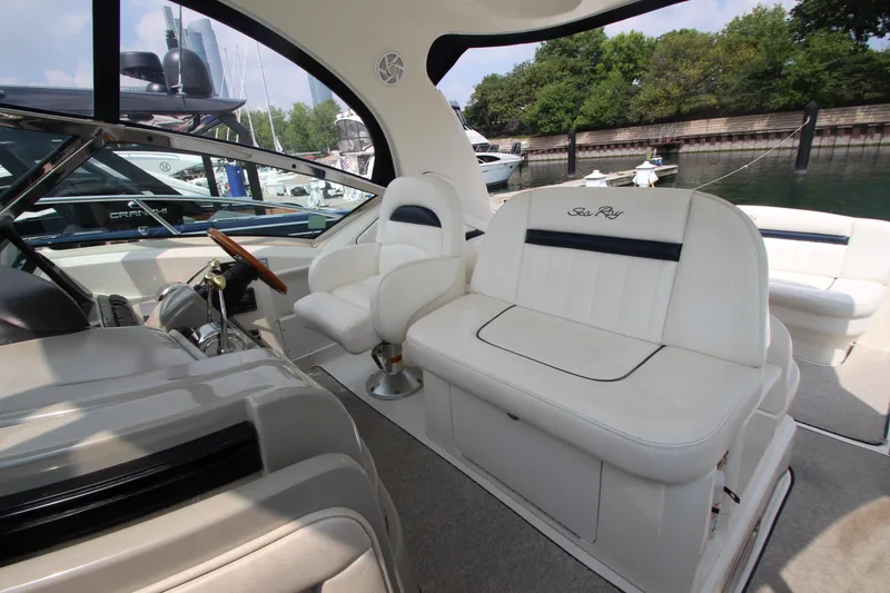 Slide: The Image of 2004 Sea Ray 40 Sundancer interior with white seating and steering wheel, docked at marina. - 28