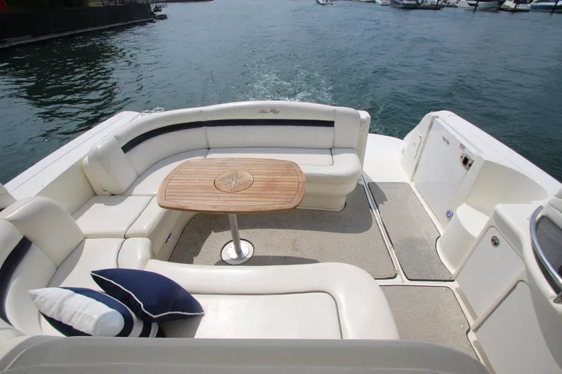 Slide: The Image of 2004 Sea Ray 40 Sundancer boat with cushioned seating and wooden table on deck. - 7