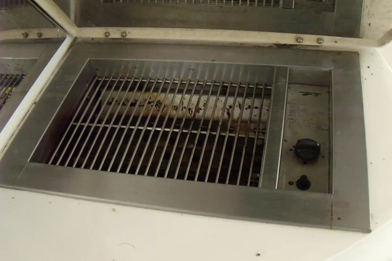 Slide: The Image of Built-in grill on 2006 Regal Commodore 4460 yacht, featuring stainless steel grates and control knob. - 13