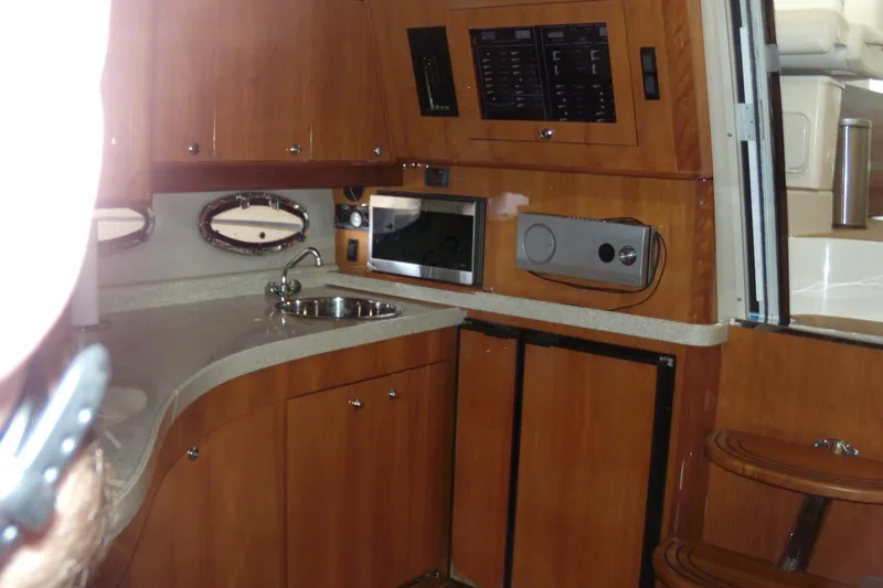 Slide: The Image of 2006 Regal Commodore 4460 yacht interior with kitchenette, featuring wood cabinets and modern appliances. - 41