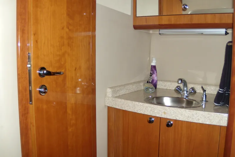 Slide: The Image of 2006 Regal Commodore 4460 yacht bathroom with wooden door, sink, and countertop. - 48