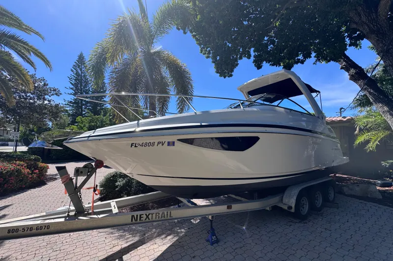 Slide: The Image of 2015 Regal 28 Express boat on trailer, parked under palm trees. - 10