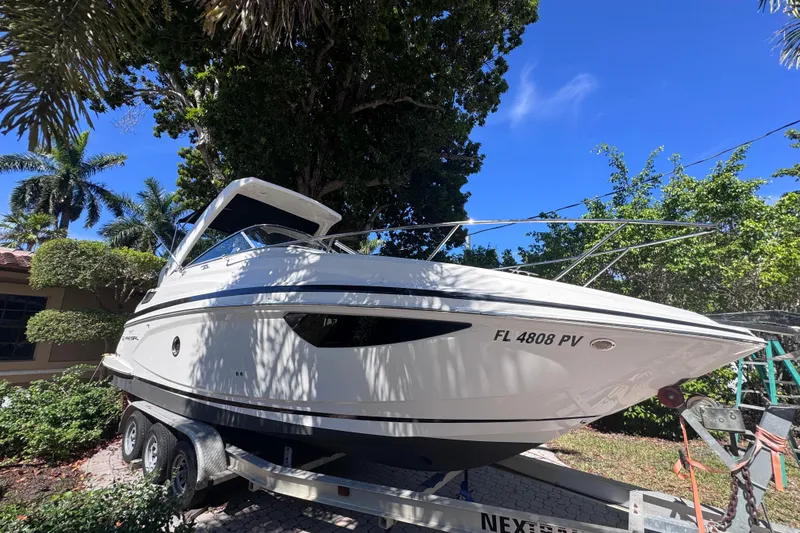 Slide: The Image of 2015 Regal 28 Express boat on trailer, surrounded by lush greenery and clear blue sky. - 2