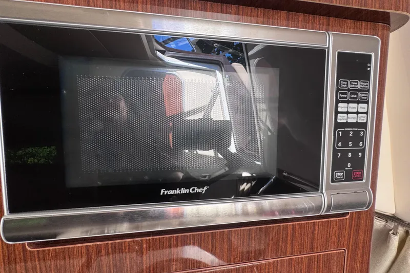 Slide: The Image of Microwave oven inside 2015 Regal 28 Express boat, featuring wood paneling and digital controls. - 22