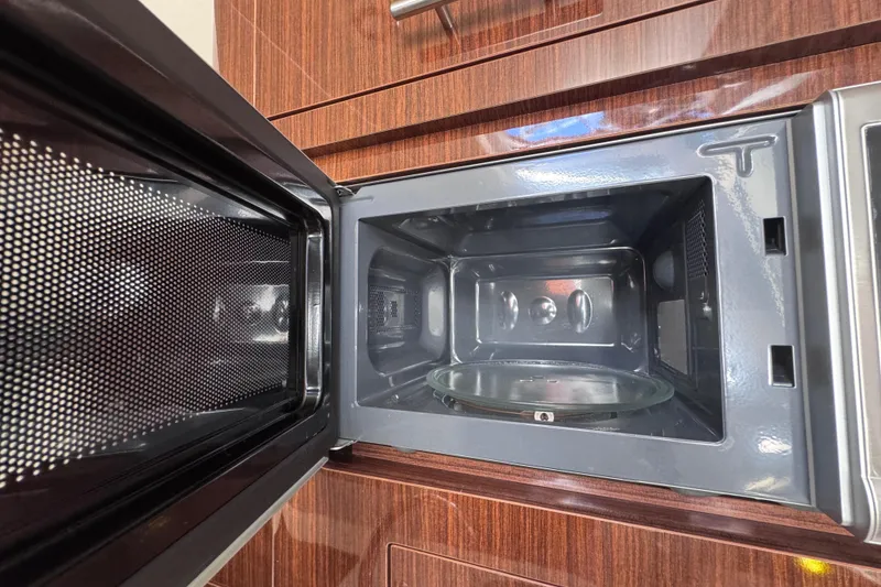 Slide: The Image of Open microwave inside a 2015 Regal 28 Express boat kitchen. - 23