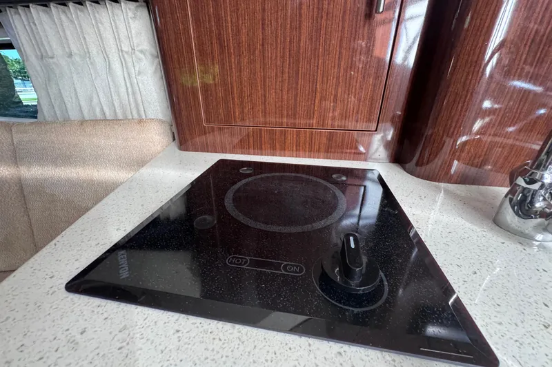 Slide: The Image of 2015 Regal 28 Express kitchen with sleek induction cooktop and wooden cabinetry. - 24