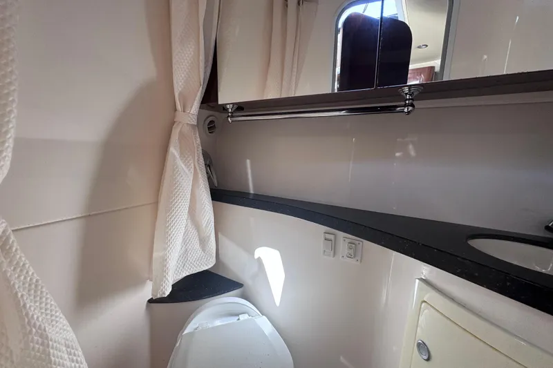 Slide: The Image of 2015 Regal 28 Express boat bathroom with modern fixtures and white curtains. - 29