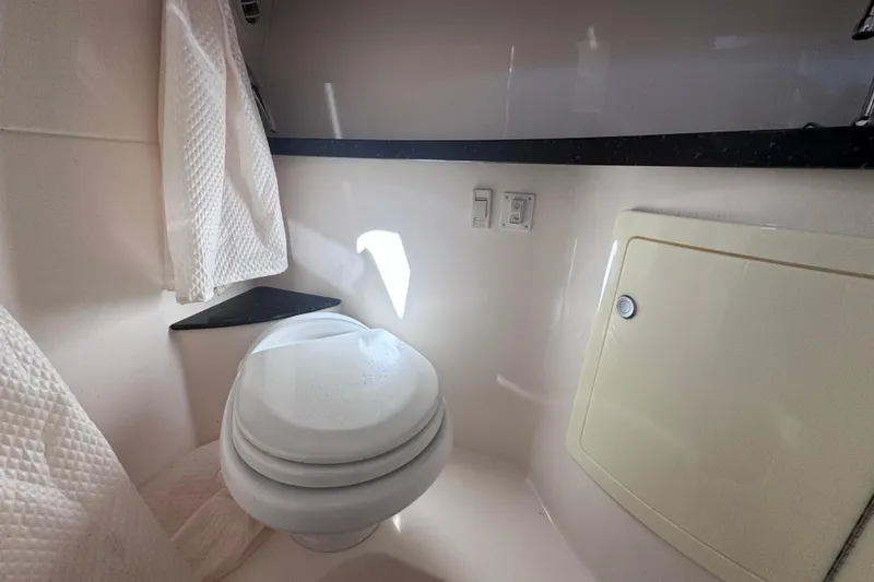 Slide: The Image of Compact bathroom in 2015 Regal 28 Express boat, featuring a toilet and storage cabinet. - 30