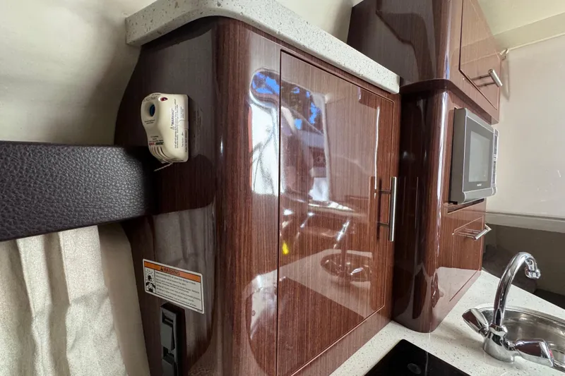 Slide: The Image of Interior of 2015 Regal 28 Express boat with sleek cabinetry and modern kitchen amenities. - 32