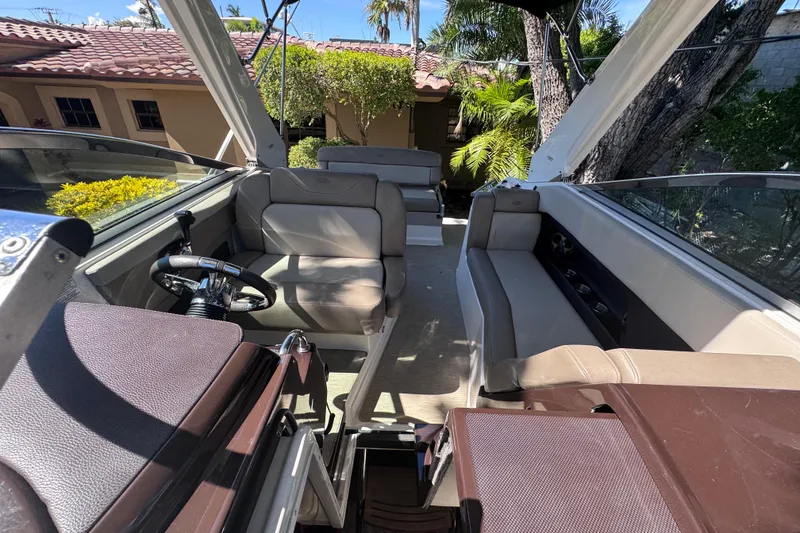 Slide: The Image of 2015 Regal 28 Express boat interior with seating and steering wheel, surrounded by lush greenery. - 36