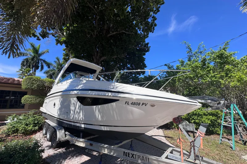 Slide: The Image of 2015 Regal 28 Express boat on trailer, surrounded by lush greenery and clear blue sky. - 4