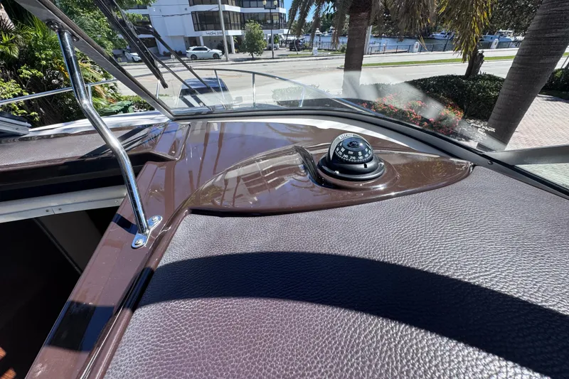 Slide: The Image of 2015 Regal 28 Express boat dashboard with compass, docked near palm trees. - 45