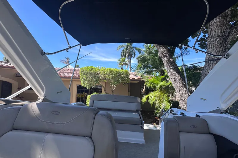 Slide: The Image of 2015 Regal 28 Express boat interior with canopy, surrounded by lush greenery. - 47