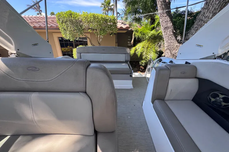 Slide: The Image of 2015 Regal 28 Express boat interior with gray seating and lush greenery background. - 48