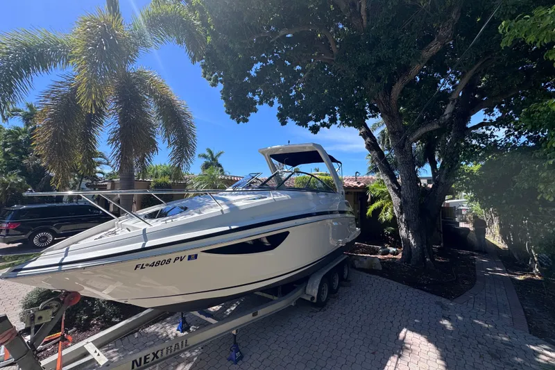 Slide: The Image of 2015 Regal 28 Express boat on trailer, parked under palm trees in a sunny driveway. - 5