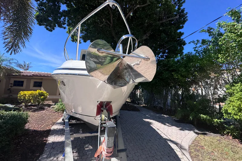 Slide: The Image of 2015 Regal 28 Express boat on trailer, surrounded by lush greenery and clear blue sky. - 6