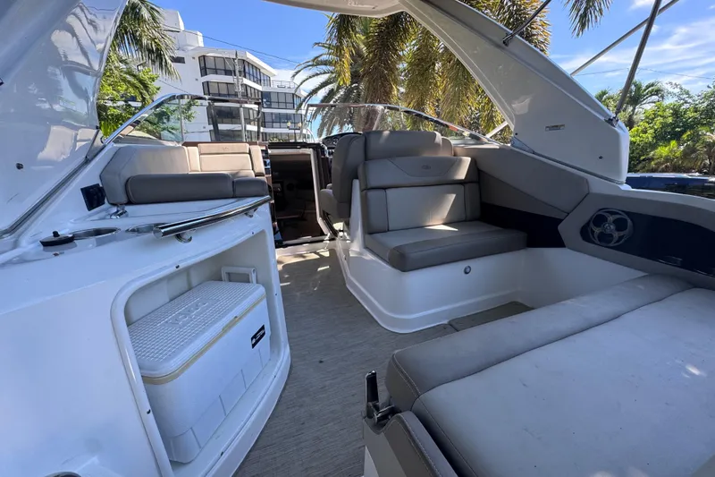 Slide: The Image of 2015 Regal 28 Express boat interior with seating, cooler, and palm trees in the background. - 64