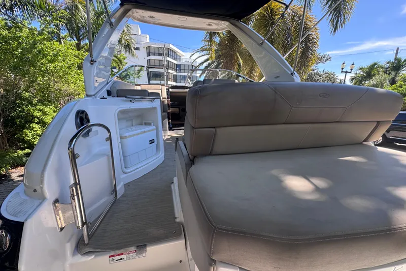 Slide: The Image of 2015 Regal 28 Express boat interior with seating and storage, surrounded by tropical greenery. - 67