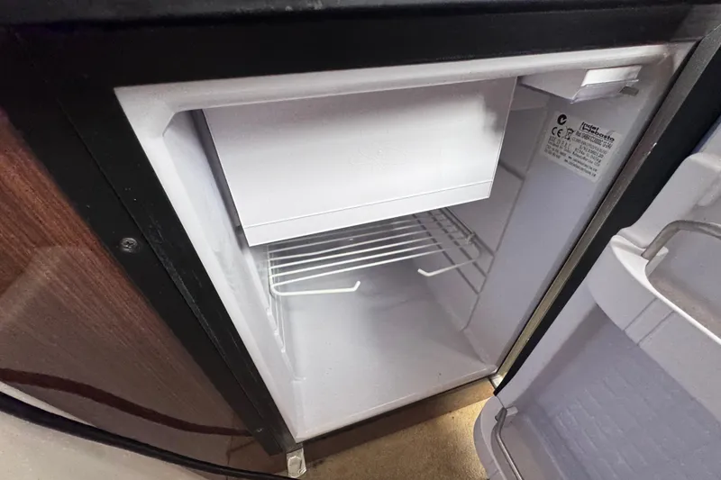 Slide: The Image of Open mini fridge inside 2015 Regal 28 Express boat, featuring a compact freezer compartment. - 69