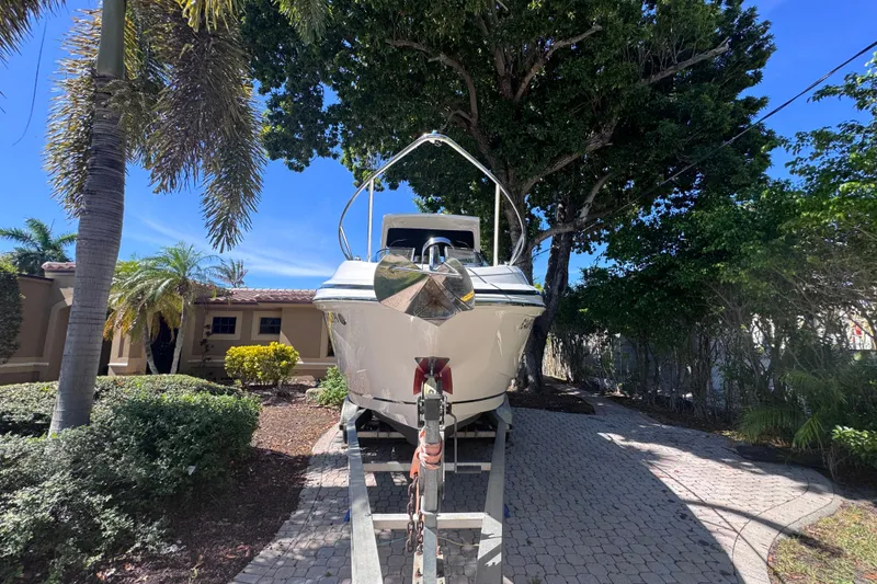 Slide: The Image of 2015 Regal 28 Express boat on trailer, surrounded by lush greenery and palm trees. - 7