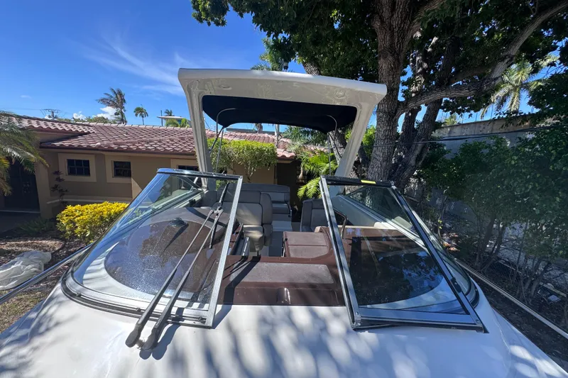 Slide: The Image of 2015 Regal 28 Express boat with open windshield, parked near a house and trees. - 73